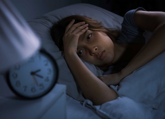 Person lying in bed in the dark, staring at the clock, struggling to fall asleep Sleep Issues